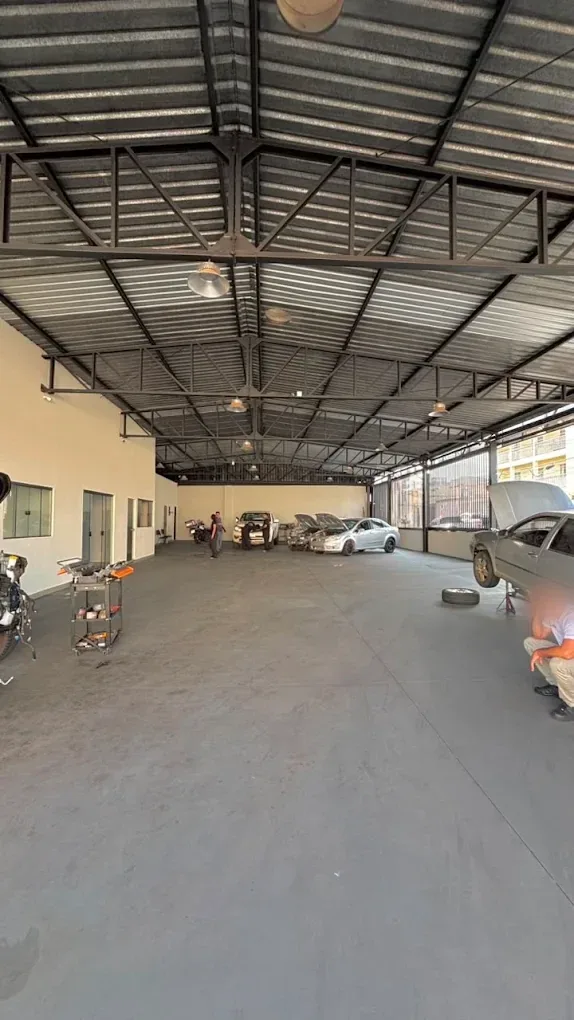Salão da oficina NexCar, amplo e coberto, com carros em manutenção